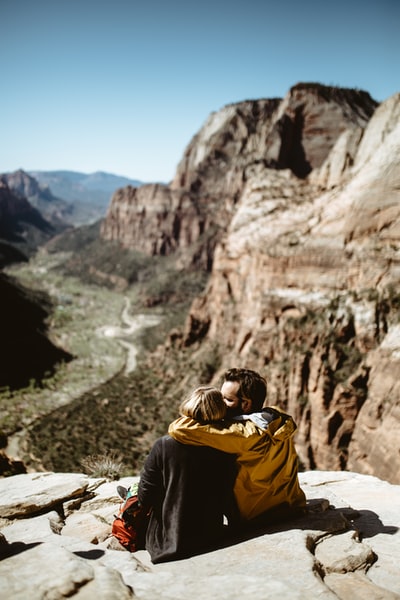 阳光下坐在岩石上的情侣选择性聚焦摄影